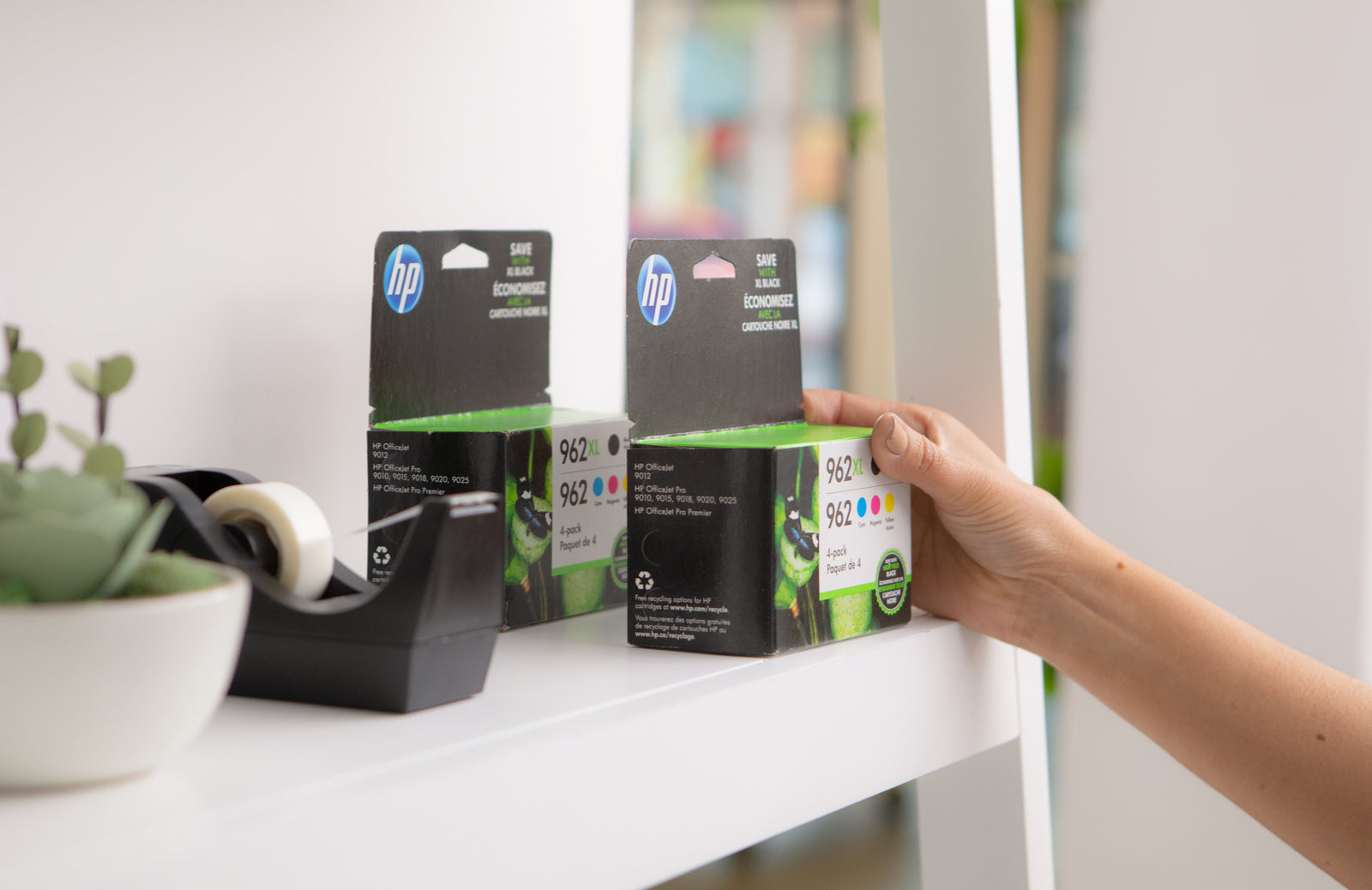 a hand reaches to collect a retail packaged HP ink cartridge off a shelf