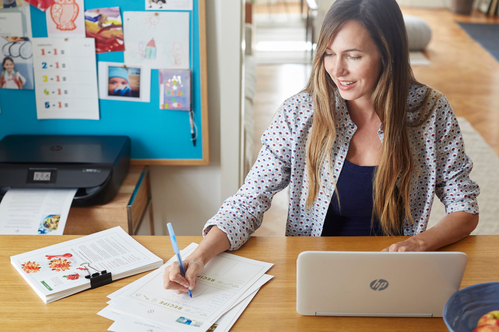 a lady works while her printer prints documents behind her