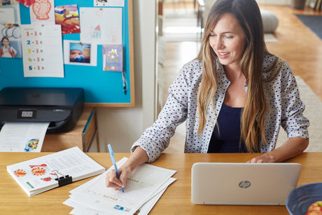 a lady works while her printer prints documents behind her