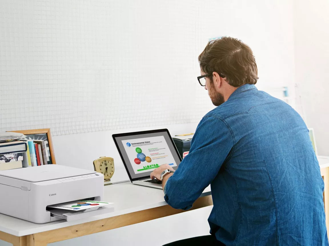 a man works in his home office using his Canon PIXMA TS4150i  printer