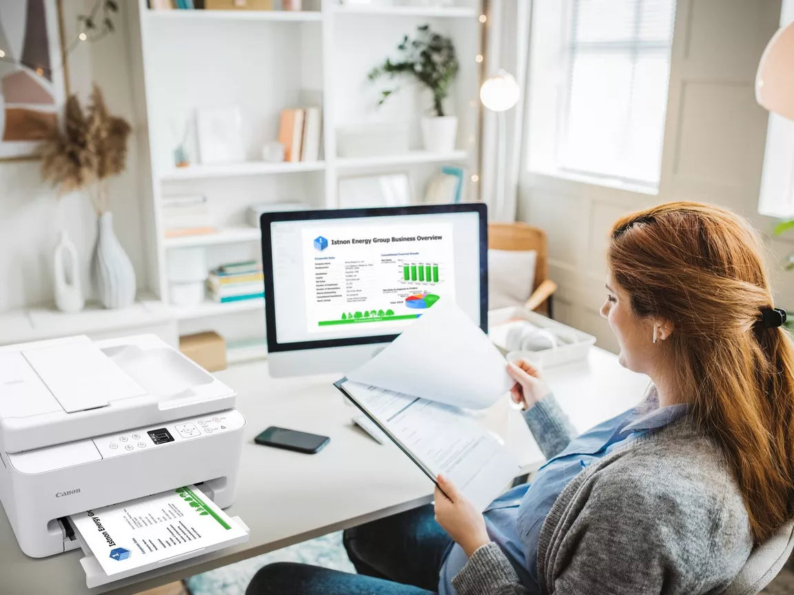 a woman looks at her printed documents from her Canon PIXMA TS7550i printer