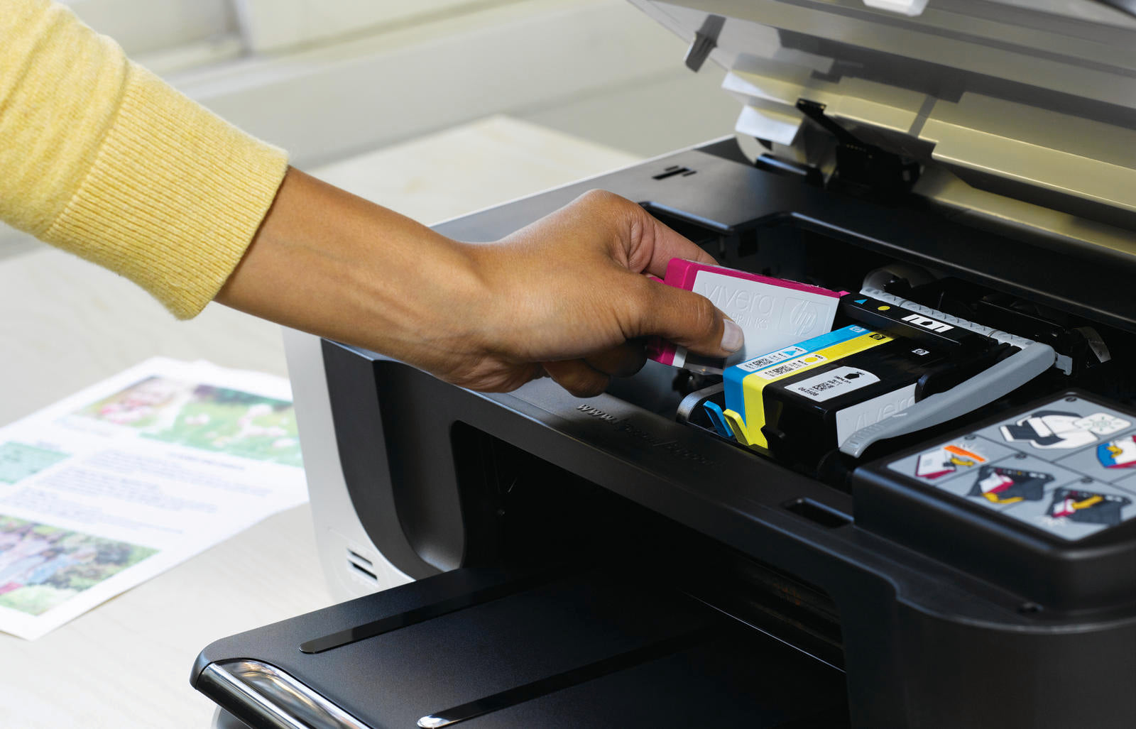 a woman loads a new magenta ink cartridge into her printer