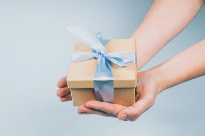A beautifully wrapped gift box is presented in someones hands