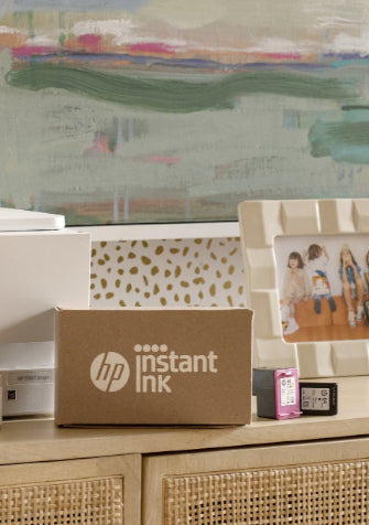 A HP Printer with a recently delivered box of hp instant ink alongside it